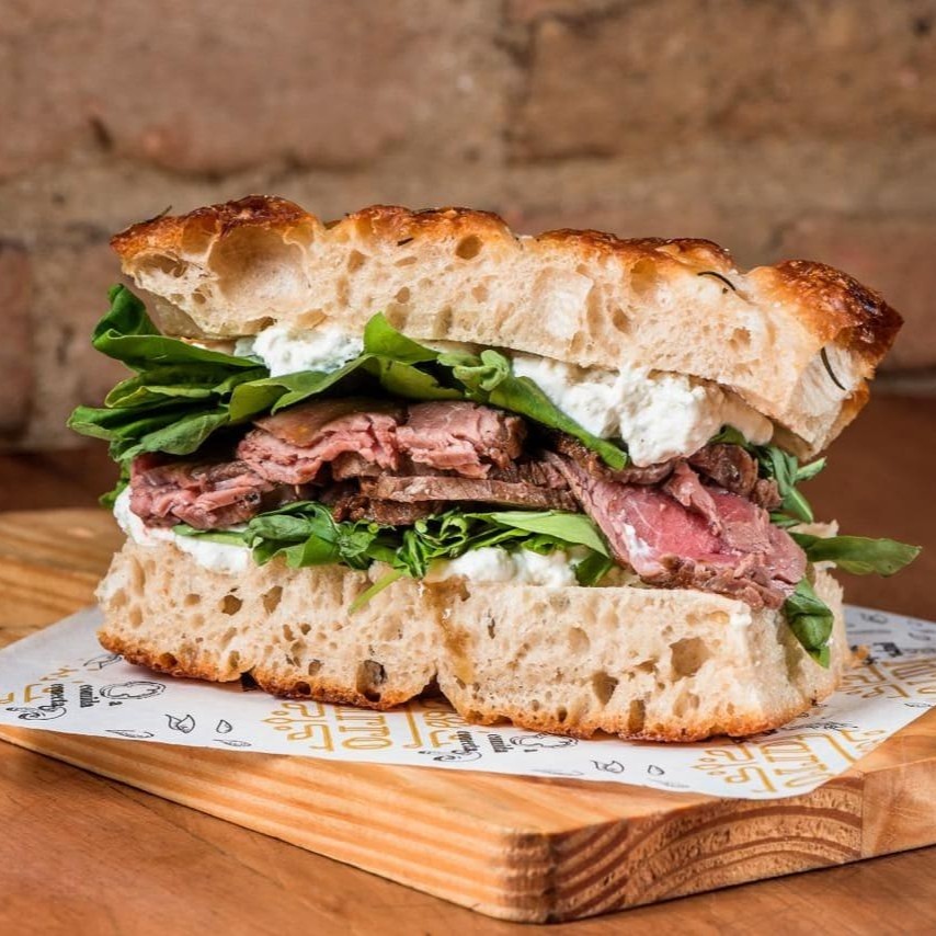 Pão focaccia, rosbife, stracciatella, rúcula, coentro, pesto, mostarda e mel.