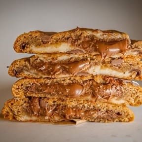 Nosso cookie duo feito com massa tradicional de baunilha, mix de gotinhas de chocolate meio amargo e chocolate ao leite, super recheado com nosso brigadeiro artesanal de Leite Ninho + Nutella! Que dupla de recheio!  Dicas: Se você gosta de um cookie bem quentinho, para uma experiência úuunica recomendamos aquecer 20s no microondas ou esquentar por 5 min a 180graus no forno. E seja feliz!!