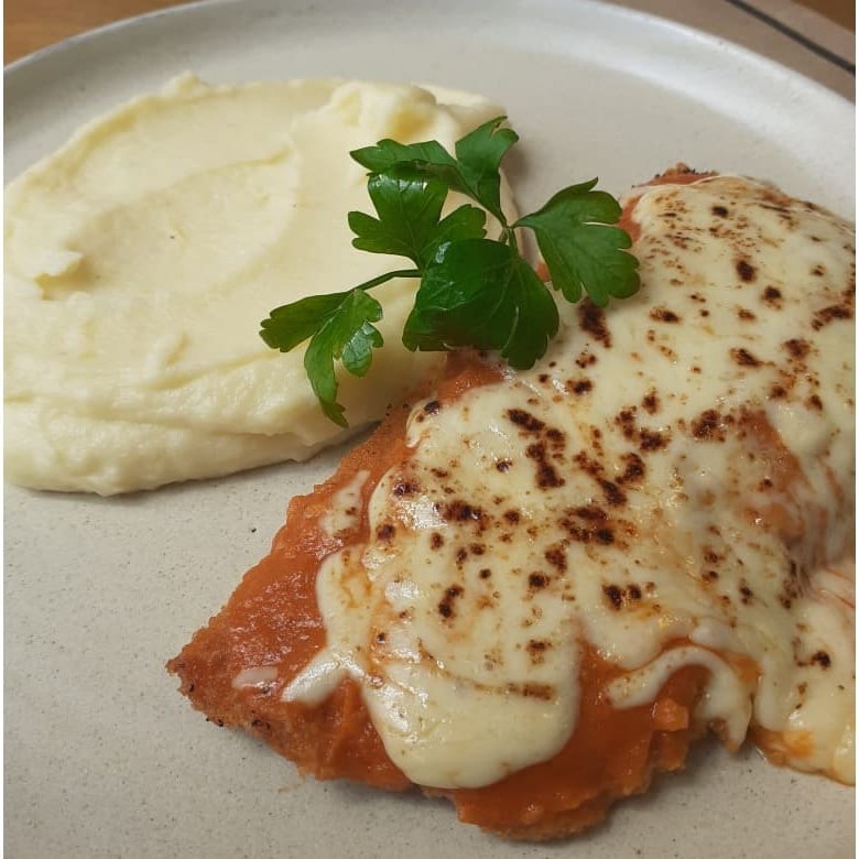 Frango crocante com molho de tomate caseiro e gratinado com queijo acompanhado de um cremoso purê de batata.