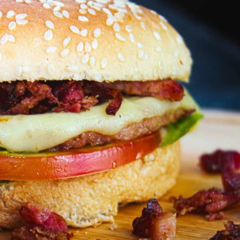 Pão com gergelim, carne, queijo, bacon, alface, tomate e molho