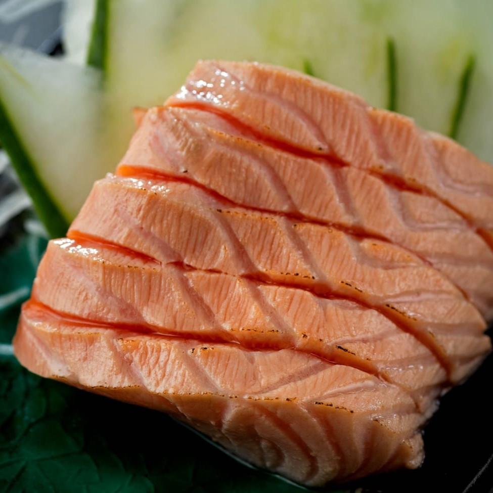 Sashimi de Salmão Selado – 5 unidades   Lâminas nobres do lombo do salmão, levemente seladas no maçarico, realçando o sabor e a textura do peixe com um toque defumado irresistível.    Um sashimi delicado, sofisticado e cheio de personalidade — perfeito para quem aprecia o melhor da culinária japonesa com um toque especial.
