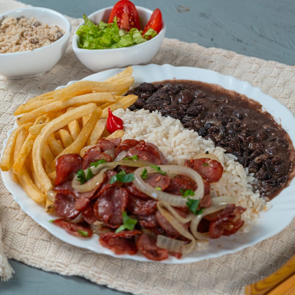 Fatias de calabresa douradas na chapa, salteadas com cebolas caramelizadas para um sabor irresistível. Acompanha arroz soltinho, feijão caseiro bem temperado, batatas fritas crocantes, salada fresquinha e farofa crocante para finalizar essa refeição deliciosa. Simples, saboroso e perfeito para qualquer momento!