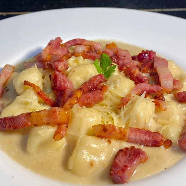 A combinação perfeita de bacon crocante e queijos ricos, para um prato de sabor irresistível. Nhoque artesanal de batata, coberto com um molho cremoso de bacon crocante e uma mistura de quatro queijos derretidos: parmesão, gorgonzola, muçarela e provolone. Uma verdadeira explosão de sabor e cremosidade que vai te deixar sem palavras. Embalagem especial e bem lacrada. Serve até 1 pessoa. Peça agora.