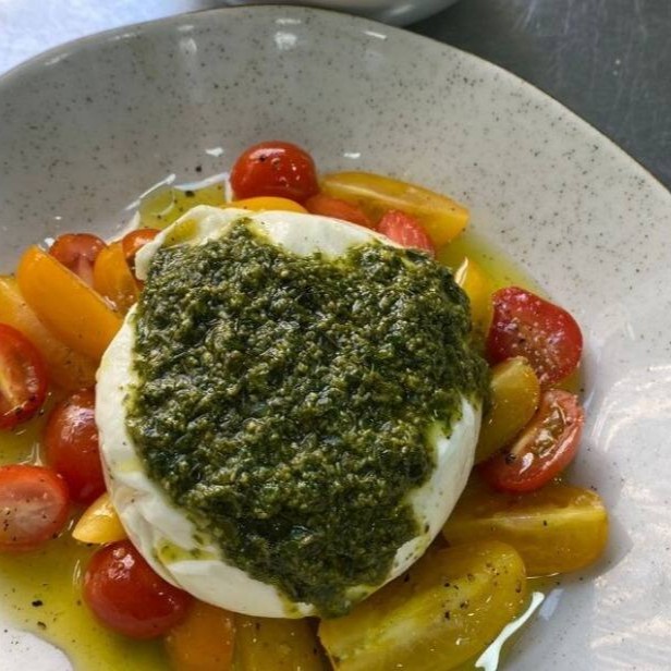 Burrata cremosa ao molho pesto  e tomate cereja. Acompanha torradas da casa.