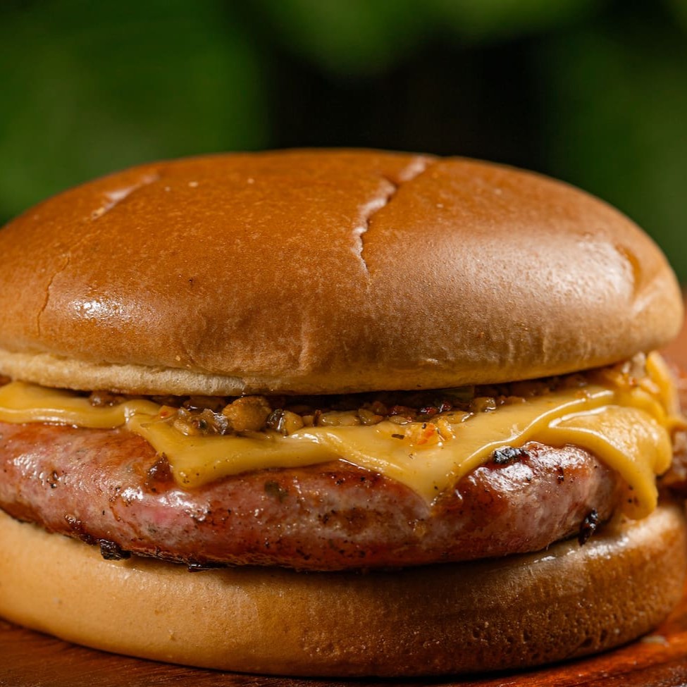 Linguiça artesanal de pernil suíno Duroc com 200g, coberto com 02 duas fatias de queijo prato e geleia de abacaxi com pimenta biquinho no pão brioche super macio.