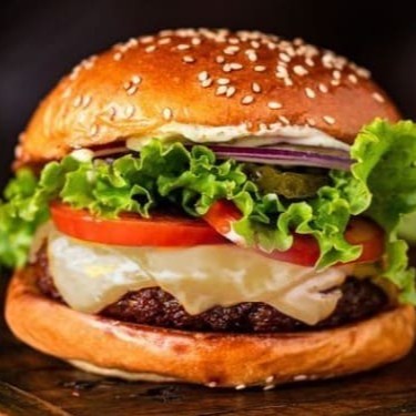 Pão brioche selado, hambúrguer artesanal de 100g, mussarela da casa, cebola roxa caramelizada, alface em dobro, tomate e maionese verde.