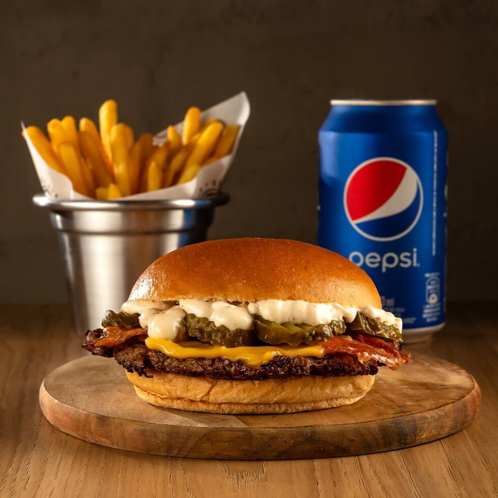 Delicioso Burger de carne black angus de 80g prensado na chapa, coberto com queijo prato, picles, bacon crocante e molho da casa à base de alho no pão brioche + batata palito P + bebida.