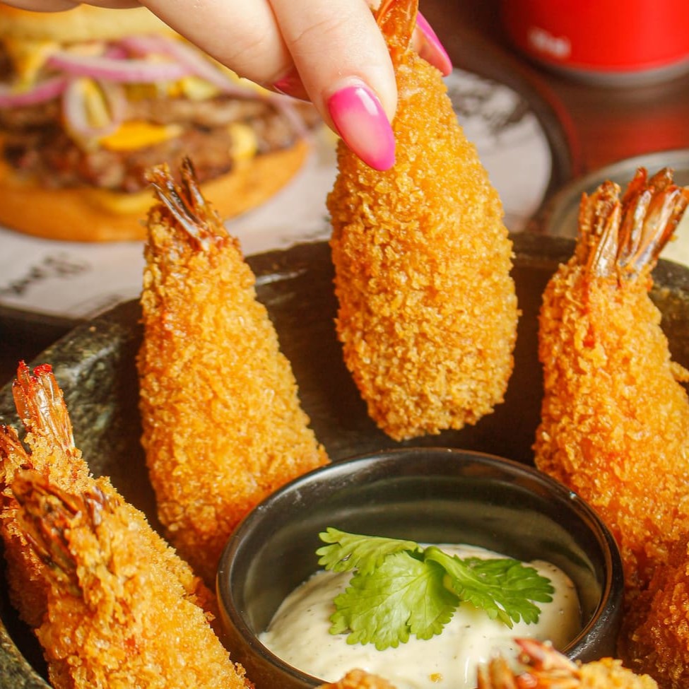 Porção com 8 tiras de camarão graúdo empanados recheados com Catupiry e acompanhados de molho ranch da casa.