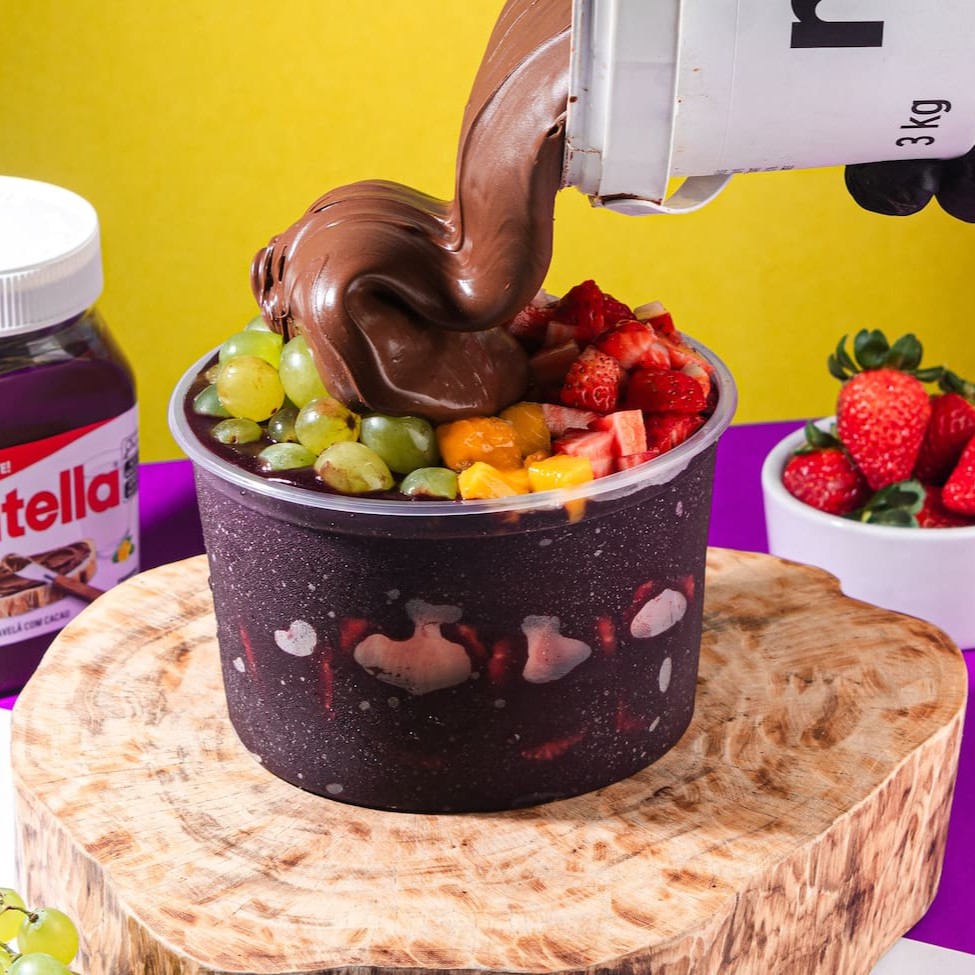 Saboreie nosso autêntico Açaí Tradicional, repleto de pedaços de frutas frescas, generosamente distribuídos no meio do copo e por cima, além disso ainda passamos Nutella no copo e colocamos por cima. Este delicioso manjar é servido em uma tigela 1l, sem economia, garantindo uma experiência gastronômica inigualável. Preparado com uma receita única e inovadora, nosso açaí é cuidadosamente batido com Guaraná, proporcionando um sabor autêntico e surpreendente, que conquista todos os paladares. Além disso, oferecemos uma variedade de complementos gratuitos, para enriquecer ainda mais a sua experiência. Uma combinação saborosa e refrescante, que vai além do convencional. Experimente e surpreenda-se com nosso 'Copo 200ml Nutella', uma inovação na categoria 'Açaí Com Frutas (Pedaços)'!