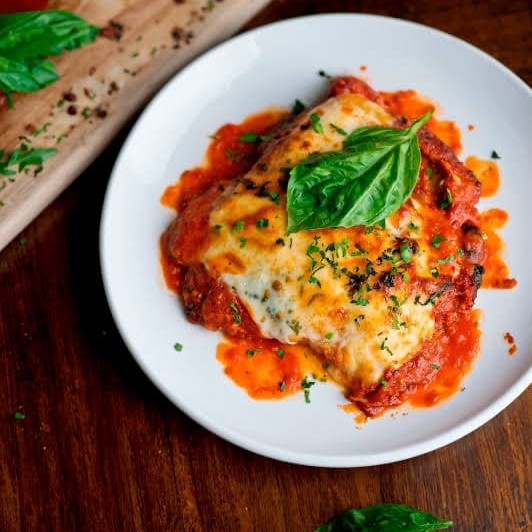 O 'Bife à Parmegiana' é a escolha perfeita para os verdadeiros apreciadores de carne. Este prato é composto por um saboroso bife, cuidadosamente empanado e coberto com um delicioso e suculento molho de tomate, complementado com uma generosa camada de queijo derretido. Acompanha um arroz soltinho e aromático, e batatas fritas crocantes e douradas. Um prato completo e irresistível, que combina texturas e sabores de forma incrível, proporcionando uma experiência gastronômica incomparável.