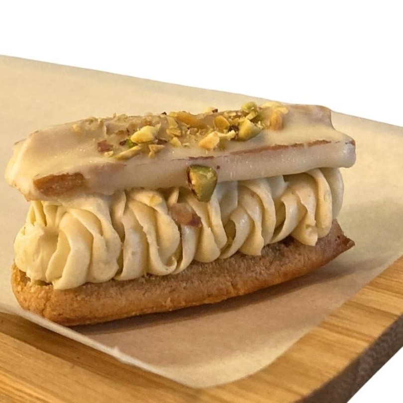 Massa choux com recheio de ganache leve de pistache artesanal finalizado com chocolate belga branco e amêndoas laminadas