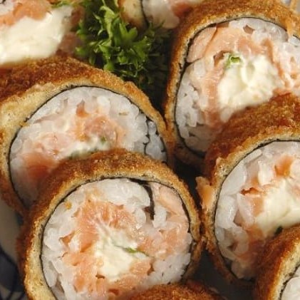 """Porção com 12 unidades de Hot Skin, sushi empanado e crocante por fora, recheado com pele de salmão grelhada até ficar dourada e saborosa, combinada com cream cheese cremoso que traz equilíbrio perfeito ao sabor. Preparado com arroz temperado na medida certa, é uma opção irresistível para quem ama sabor marcante e textura crocante."""