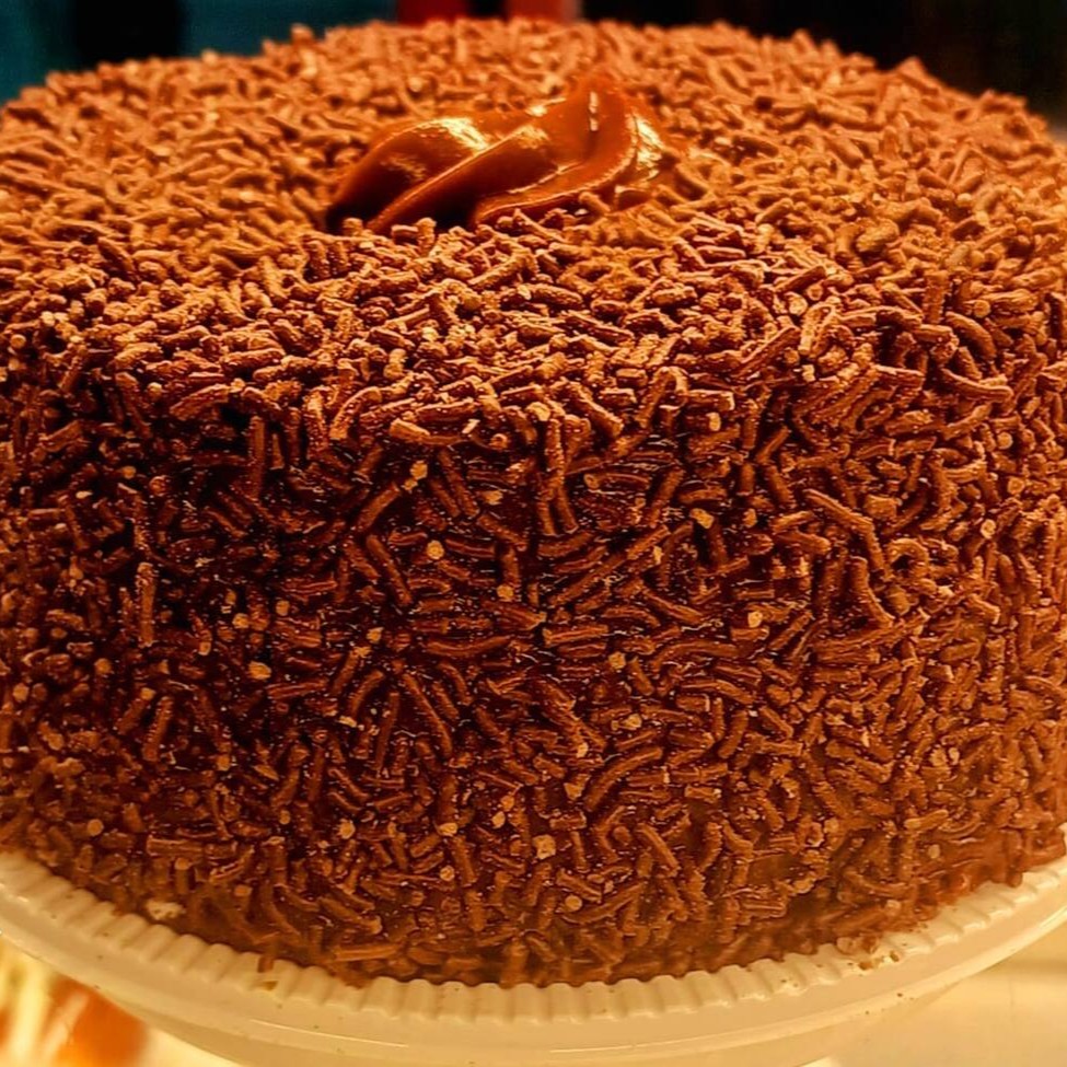 Tão sedutor quanto irresistível, nosso 'Bolo de Chocolate Coberto de Granulado' é um autêntico deleite para os verdadeiros apreciadores de chocolate. Cuidadosamente preparado, este bolo se destaca por sua massa úmida e opulenta de chocolate, permeada por um sabor intensamente rico. Generosamente revestido por uma camada de granulados de chocolate, ele oferece uma textura crocante, que contrasta de maneira sublime com a maciez inegável do bolo. A escolha perfeita para celebrações ou apenas para saciar aquela vontade de chocolate. Esse bolo é uma tentação à qual você não vai querer resistir!