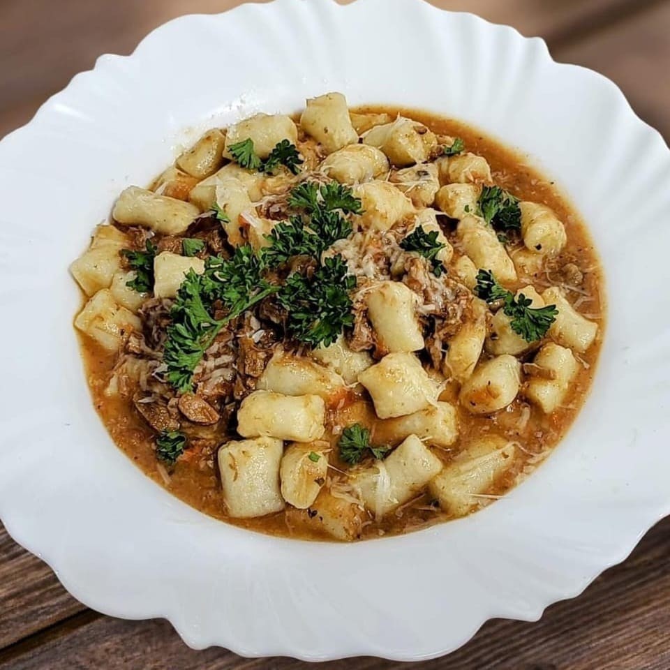 Nosso 'Nhoque de Batata ao Molho Ragu Bolonhesa', categorizado como 'Os Queridinhos', é um dos pratos mais cobiçados de nosso cardápio. Ideal para os verdadeiros apreciadores da autêntica culinária italiana, esta massa de batata divinamente bem elaborada é harmoniosamente servida com um molho à Bolonhesa intensamente rico e saboroso. Nossa carne é meticulosamente picada na ponta da faca e cozida lentamente para liberar todos os seus sabores e aromas cativantes. Este é um prato indulgente que mescla texturas macias com um sabor vigoroso e memorável. Venha experimentar e descobrir o porquê do 'Nhoque de Batata ao Molho Ragu Bolonhesa' ser um dos nossos pratos mais amados.