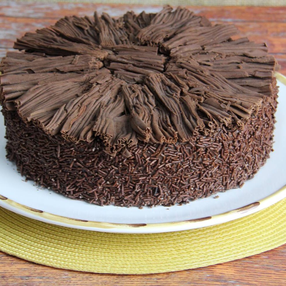 Bolo fofinho de chocolate recheado e coberto de puro brigadeiro. Coberto com lascas de chocolate ao leite.  Diâmetro de 24 cm servindo aprox. 20 fatias.