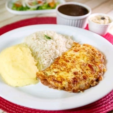 Prato simples, mas delicioso, com omelete feito com tomate fresco, cebola e mussarela derretida. Acompanha arroz soltinho, feijão saboroso, farofa crocante com calabresa (em embalagem separada) e mais um acompanhamento que desejar.  Nossas refeições são servidas em embalagem de isopor de aproximadamente 700ml.