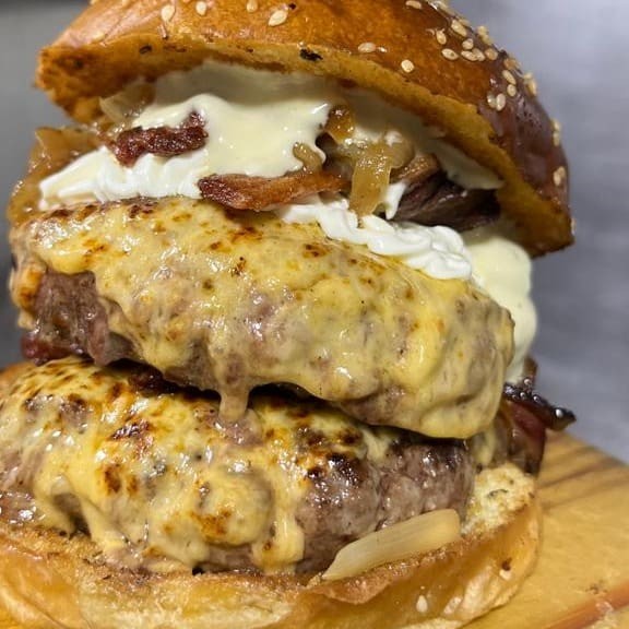 Nosso Gigante Thanos com 2 Blends Bovinos de 200g Cada Ao Ponto da Casa, Queijo Derretido, Bacon Crocante, Cream Cheese,Cebola Caramelizada e Maionese Caseira.