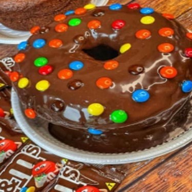 Delicie-se com o nosso Bolo de M&M's, uma maravilha que provém da categoria 'Bolos - 1kg - 16 fatias'. Esta deliciosa iguaria consiste num suculento bolo de chocolate com generosos 20cm de diâmetro, exibindo uma incrível cobertura de brigadeiro. Mas aguardem, há mais! Para finalizar com um toque de mestre, o bolo é habilmente coroado com uma profusão de M&M's, adicionando uma explosão de cores e s