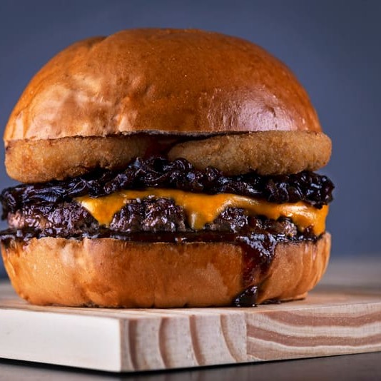 1 burger 160gr. De ribeye, 1 camada de cheddar, molho barbeque, cebola caramelizada e onion rings