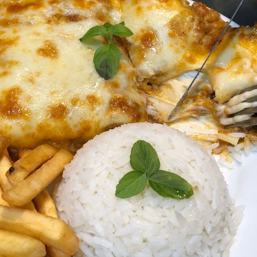 Uma deliciosa lasanha de frango acompanhada por arroz e fritas crocantes.
