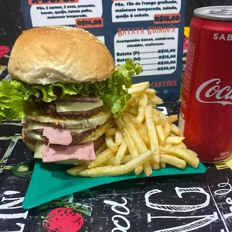 O 'X Larica' é um lanche para os verdadeiros amantes de carnes. Oferece uma combinação irresistível de cinco diferentes carnes suculentas, acompanhadas de três ovos bem cozidos. O pão, sempre fresco e macio, abriga generosas camadas de queijo derretido e presunto de alta qualidade. O toque especial fica por conta da maionese temperada, que adiciona um sabor único e irresistível ao lanche. A calabresa dá um toque apimentado que equilibra perfeitamente com o adocicado do ketchup. Uma verdadeira explosão de sabores em cada mordida!