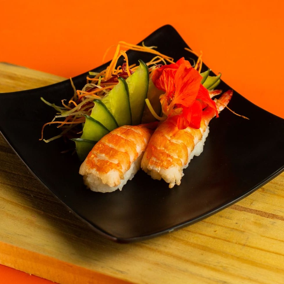 """Sushi de camarão com 4 unidades preparado com arroz temperado no ponto certo e camarões frescos e cozidos, cuidadosamente posicionados sobre a base de arroz para garantir textura e sabor irresistíveis. Uma combinação leve e saborosa, perfeita para quem aprecia frutos do mar na culinária japonesa."""