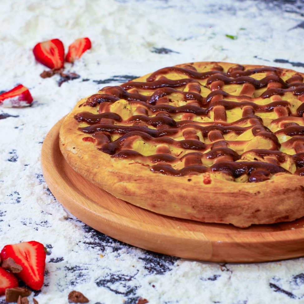 Pizza Doce de 30cm, generosamente recheada para uma experiência gastronômica irresistível. Cada mordida revela uma montanha de recheio, tão abundante que é quase impossível não se lambuzar. Utilizamos o autêntico chocolate Nestlé, proporcionando uma doçura equilibrada e um sabor irresistível. Esse é um prato para os verdadeiros amantes de chocolate, com recheio que parece nunca acabar. Uma delícia para ser saboreada sem pressa, cada fatia é um convite à indulgência.