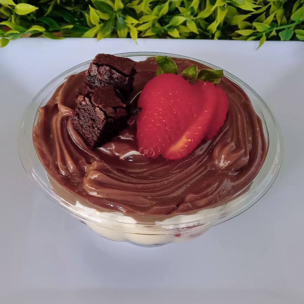 A 'Torta de Morango com Brownie' é uma combinação perfeita de chantilly trufado, enriquecida por pedaços generosos de brownie. O recheio de chocolate branco e chocolate tradicional, conferindo um sabor surpreendente. A cereja do bolo, ou melhor, o morango da torta, são os morangos frescos, adicionados não apenas por sua beleza, mas também pelo seu sabor vibrante e fresco.