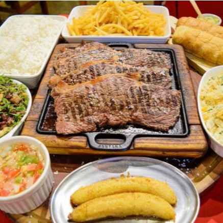O '122 Alcatra Família para 4 Pessoas' é uma celebração de sabores autênticos do nosso churrasco na pedra. A suculenta alcatra é acompanhada de um arroz soltinho, feijão tropeiro temperado com perfeição e batatas fritas crocantes. O prato é realçado com um molho caseiro rico em sabor, e uma farofa de ovos que traz a crocância ideal. A experiência fica completa com a doçura da banana frita e a cremosidade do nosso creme de alho especial, delicadamente temperado com ervas finas. Ideal para compartilhar em família ou com amigos, este prato é um convite à boa mesa e ao prazer de saborear a culinária brasileira.