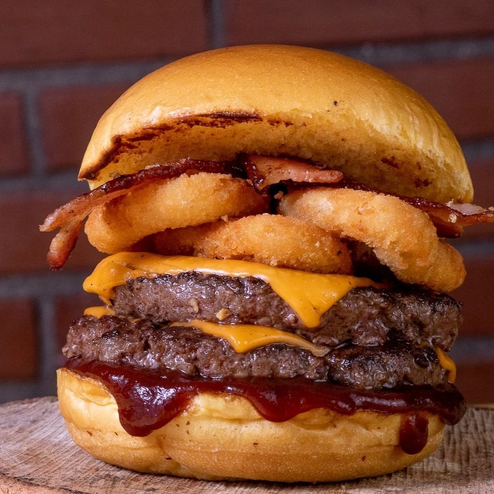 Pão de brioche, 2 Blends Angus 100g, queijo 2x, bacon, anéis de cebola empanados e Molho Barbecue Defumado
