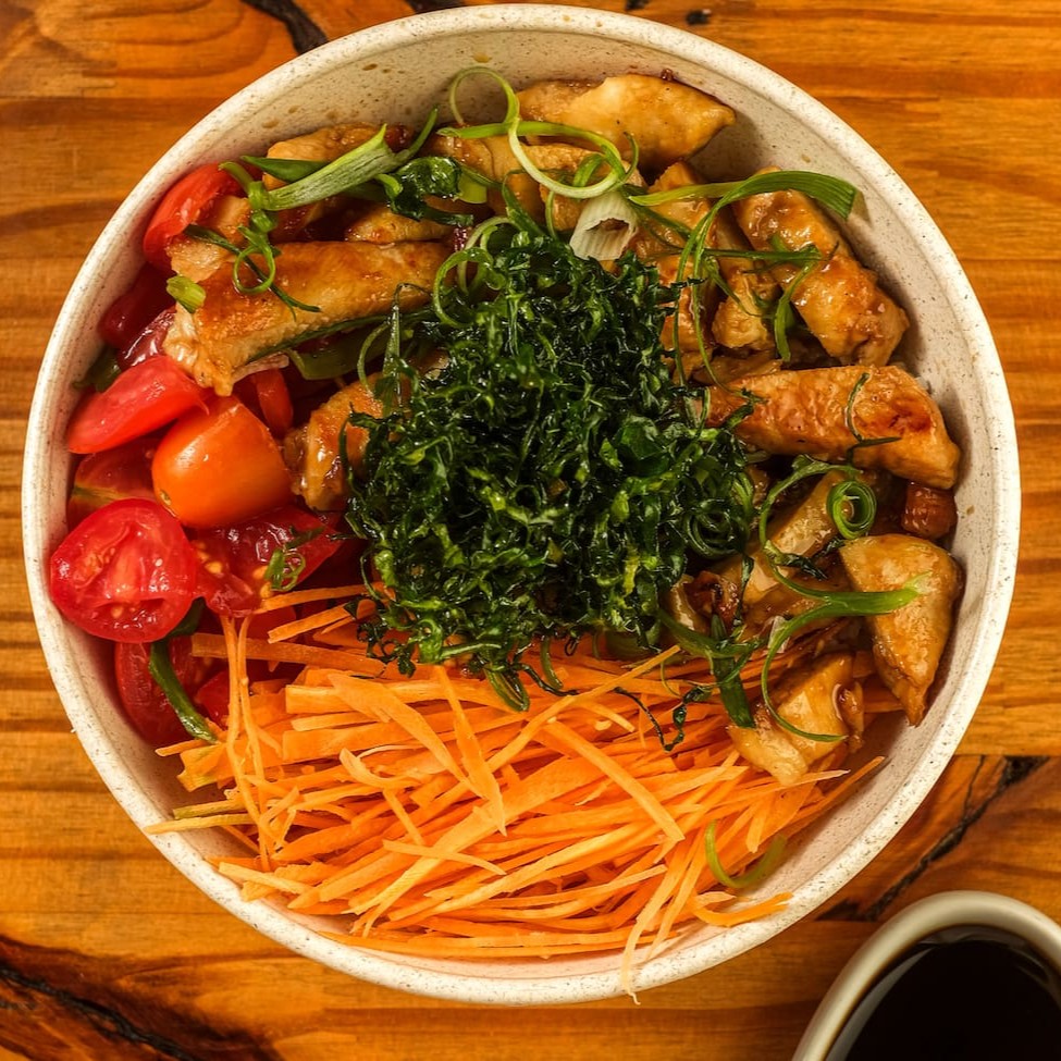 Base de arroz gohan, frango grelhado com toque de molho teriyaki, gengibre fresco, tomate cereja, cenoura, finalizado com cebolinha e couve crispy. Acompanha Koa molho havaiano.
