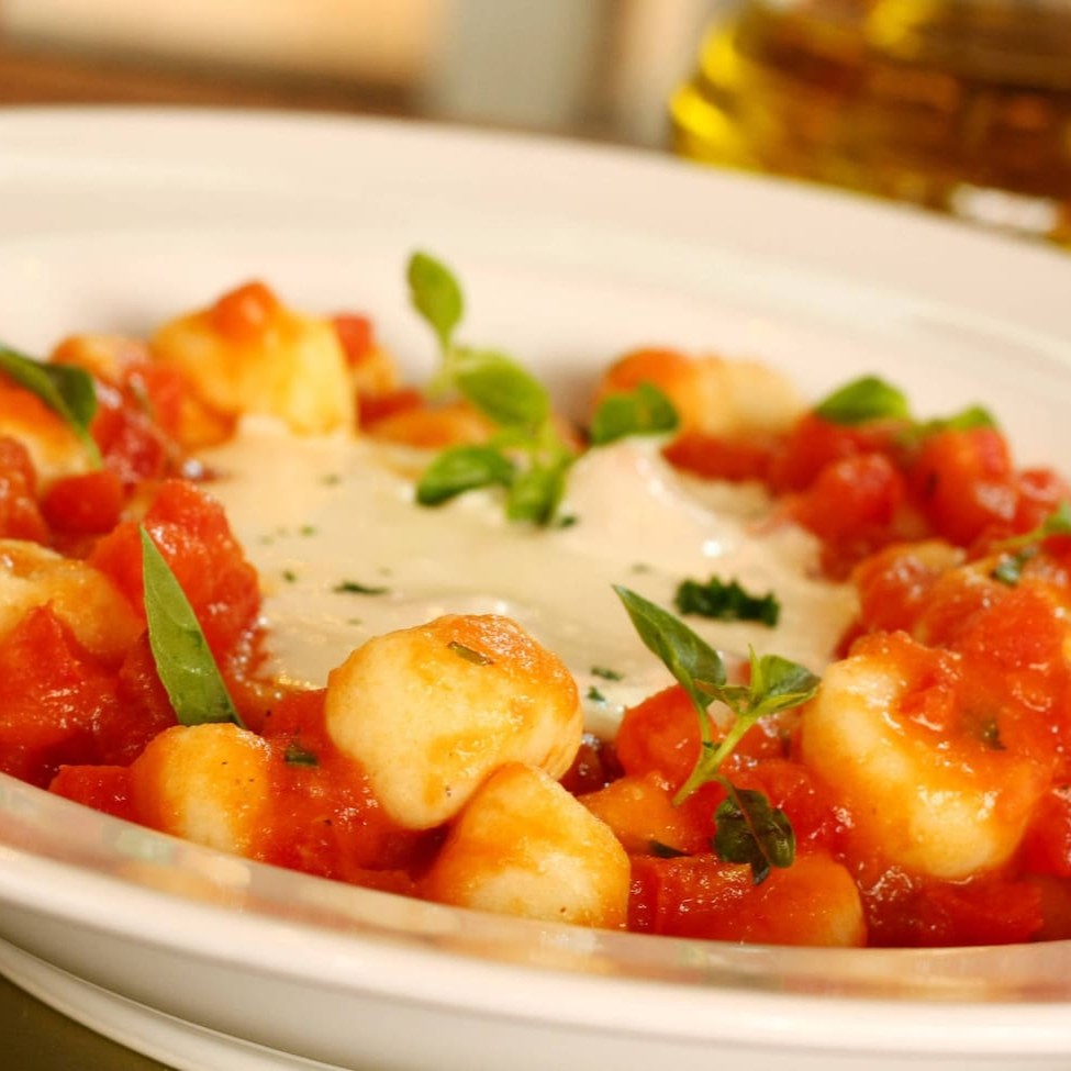 Delicie-se com nosso suntuoso Gnocchi (Nhoque) ao Molho Pomodoro, cuidadosamente preparado e generosamente servido em porções de 400g, 500g ou 800g. Este prato clássico da culinária italiana é enriquecido com pedaços frescos e suculentos de tomate, imergindo cada gnocchi numa explosão de sabor. O molho pomodoro, autêntico e caseiro, reveste cada pedaço, criando uma harmonia perfeita entre a massa leve e o rico sabor do tomate. Um prato da categoria 'Gnocchi Molhos Tradicionais' que promete uma experiência gastronômica inesquecível.