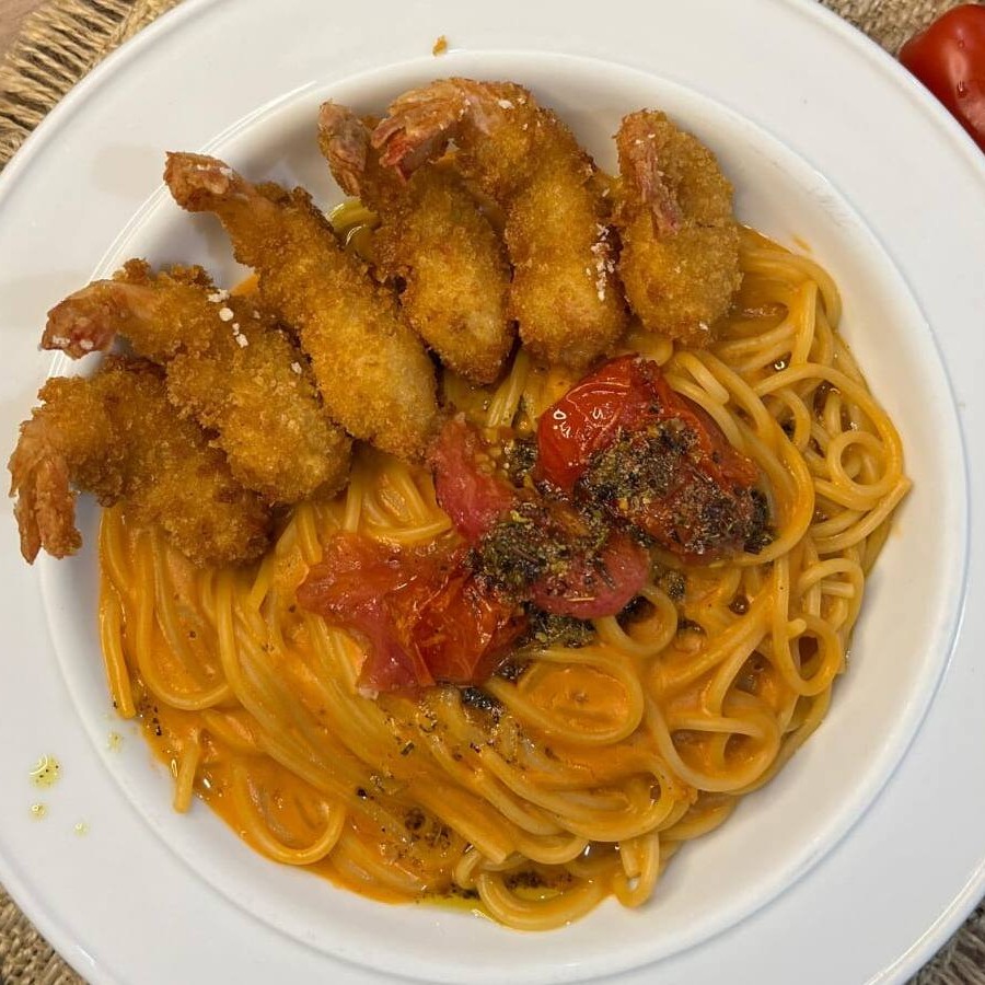 "Camarões empanados, dourados e crocantes, acompanhados por um refinado molho bisque, que destaca o sabor marcante dos frutos do mar. Finalizado com tomates-cereja frescos e um toque de molho chimichurri, trazendo um equilíbrio perfeito entre frescor e intensidade. Uma combinação irresistível de texturas e sabores."""