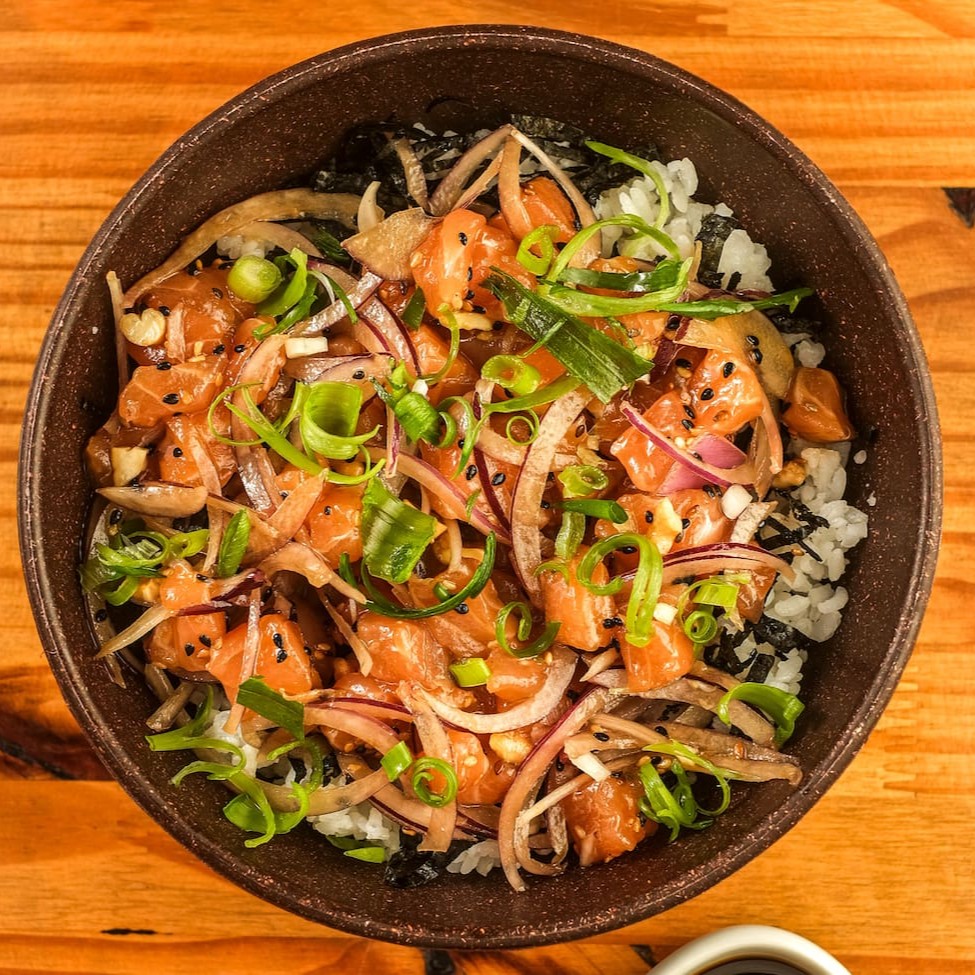 Arroz gohan temperado com alga nori, cubos de salmão marinados no Koa molho havaiano temperados com cebola roxa, gergelim e castanha de caju torrada, finalizados com cebolinha. Acompanha Koa molho havaiano.