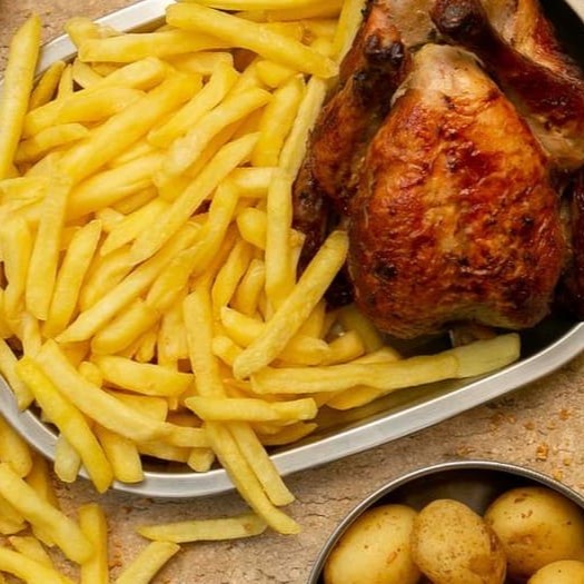 Frango inteiro assado na brasa acompanhado de porção de batata frita.