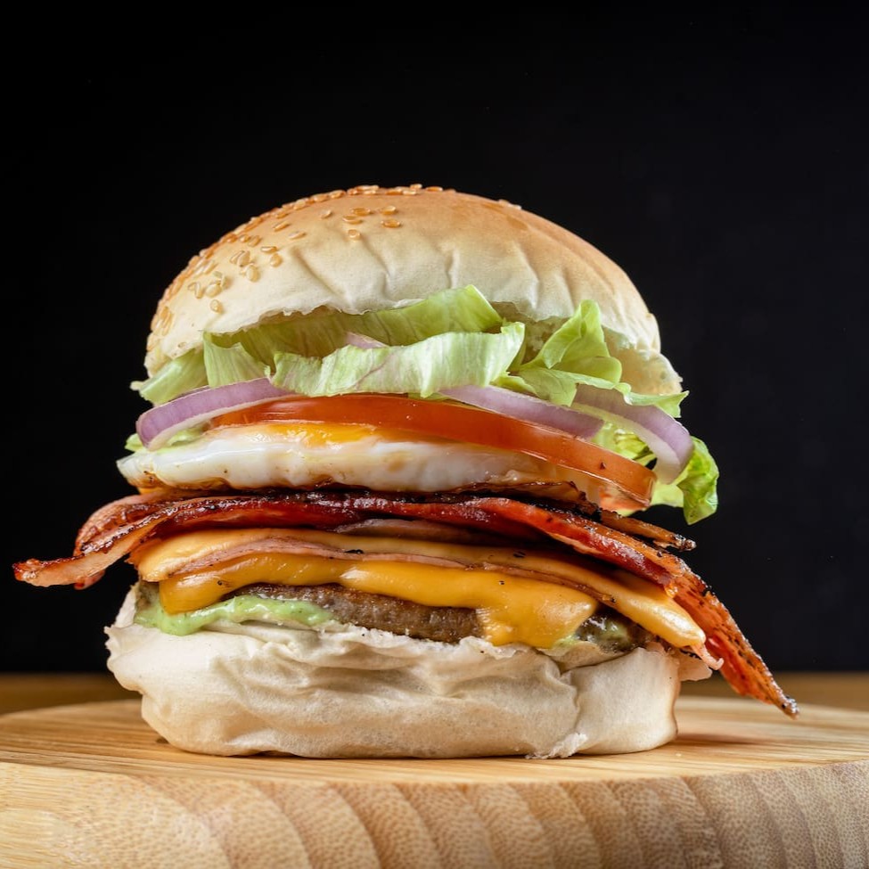 X-tudo completo e cheio de moral: pão macio, carne suculenta, queijo, presunto, bacon crocante, ovo, salada e molho verde. Um clássico de responsa — pesado, saboroso e carioca na essência!