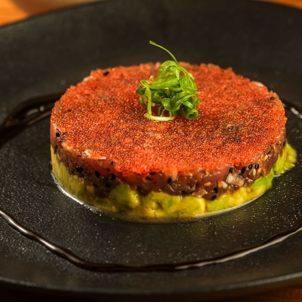 Atum, abacate, cebolinha, cebola roxa, gergelim, pimenta Sriracha, Koa molho havaiano, finalizados com ova de peixe. Acompanha tortilha de milho crocante.