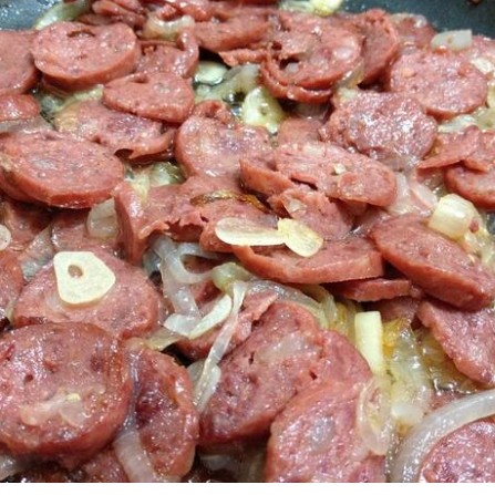 Porção de linguiça calabresa acebolada.