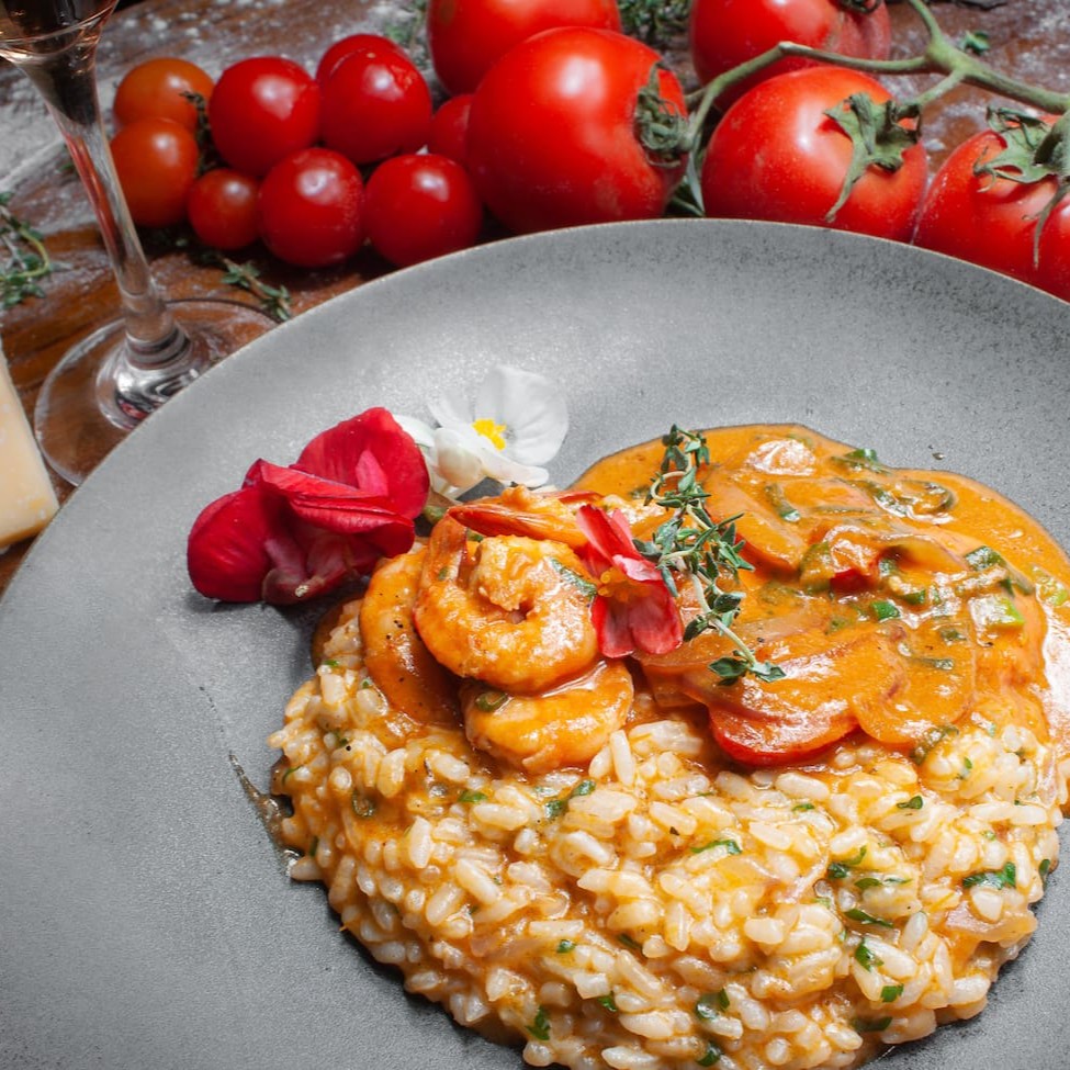 Delicie-se com o nosso delicioso risoto de camarões! Feito com arroz arbório cozido lentamente em um caldo rico e saboroso de frutos do mar, esse prato é recheado com camarões suculentos e tenros, tomate cereja, cebola roxa, leite de coco, molho de tomate artesanal e queijo parmesão derretido.