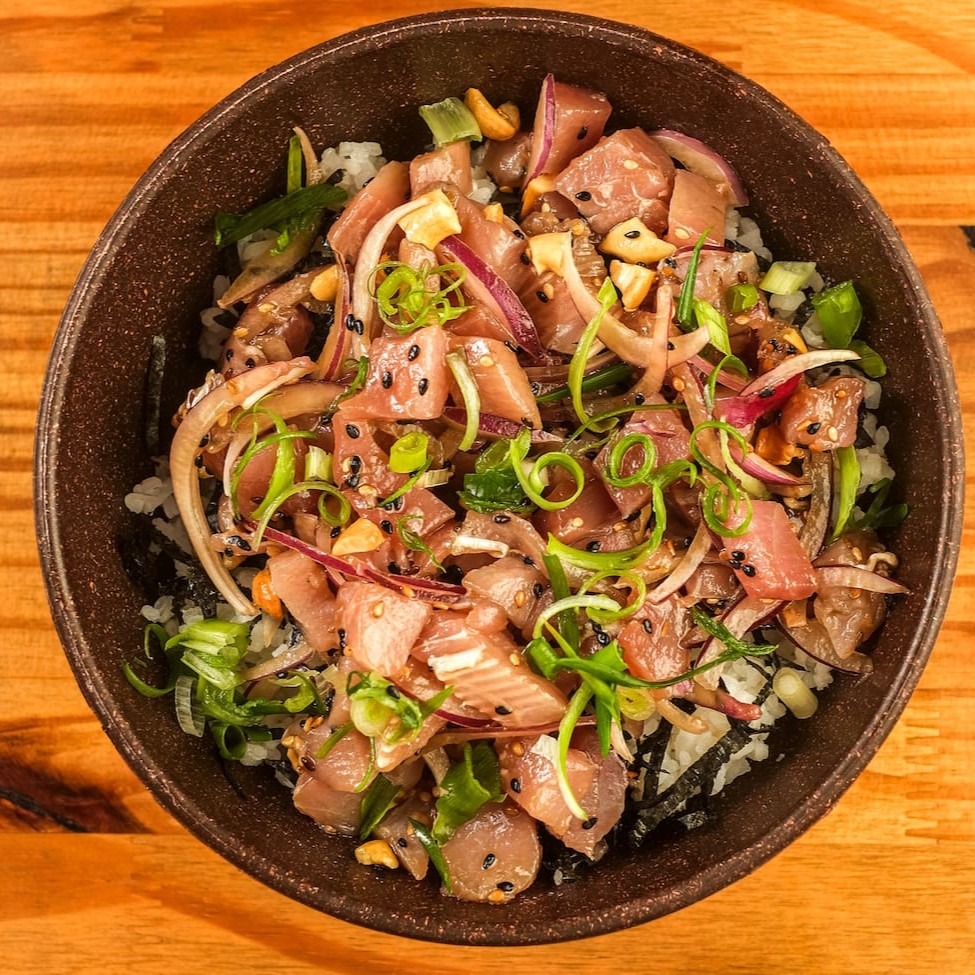 Nossa versão do mais tradicional poke havaiano, leva base de arroz japonês temperado com alga nori, proteína de atum em cubos marinado e temperado com cebola roxa, gergelim, castanha de caju torrada, finalizado com cebolinha. Acompanha Koa molho havaiano.