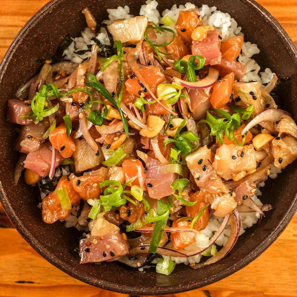 Salmão, peixe branco e atum temperados com cebola roxa, gergelim e castanha de caju torrada, marinados no molho havaiano, servidos sobre a base de arroz japonês e alga nori, finalizados com cebolinha. Acompanha Koa molho havaiano