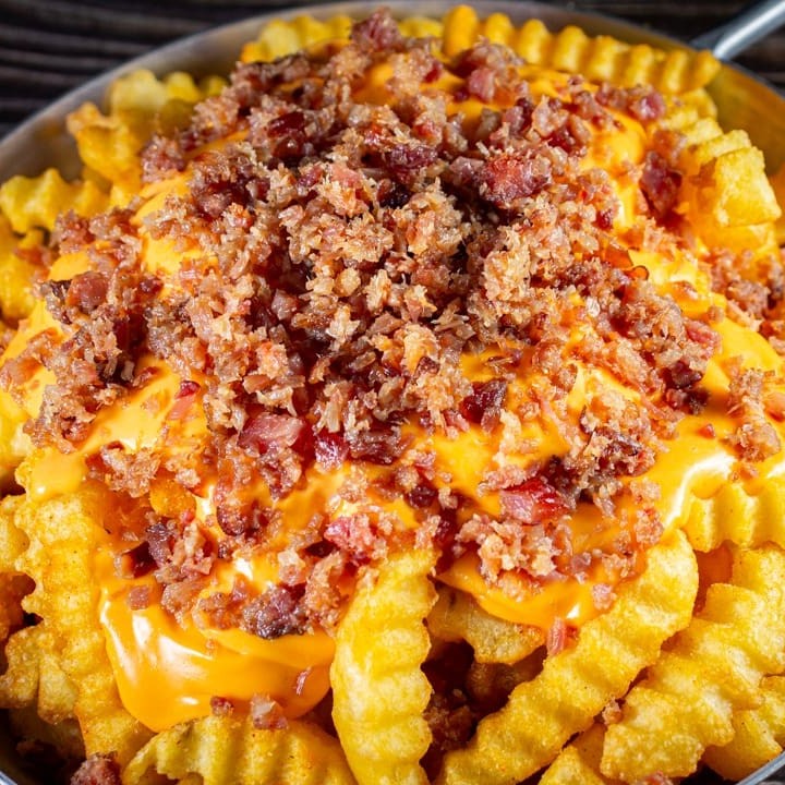 Batata crinkle crocante por fora e macia por dentro, coberta com cheddar e farofa de bacon.