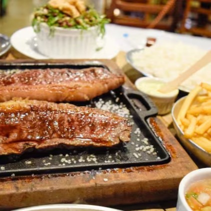 Delicie-se com a nossa '102 - Picanha com Guarnição - 2 Pessoas', uma opção deslumbrante da categoria 'Churrasco na Pedra'. Este prato generoso traz a picanha, suculenta e saborosa, acompanhada de uma seleção exuberante de guarnições. Aprecie o arroz soltinho, o feijão tropeiro autêntico, as fritas crocantes e o molho irresistível. Acompanha ainda uma farofa dourada, perfeitamente preparada, e a doçura inconfundível da banana frita. Para finalizar com chave de ouro, um creme de alho especial, enriquecido com ervas finas. Um banquete para duas pessoas que valorizam a boa culinária!