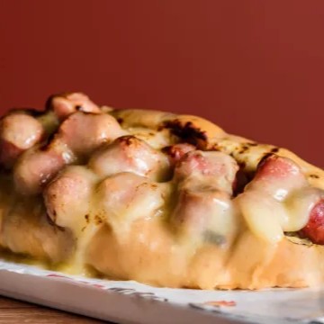 Delicioso pão baguete recheado com pasta de alho da casa, linguiça mineira e queijo maçaricado.