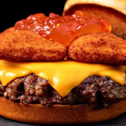 Blend bovino 150g Angus, duas fatias de cheddar uruguaio derretido, deliciosas e crocantes almofadinhas de queijo gouda empanado, geleia de pimenta levemente adocicada, finalizado em um pão brioche macio e selado na manteiga. Para dar uma apimentada na sua noite!