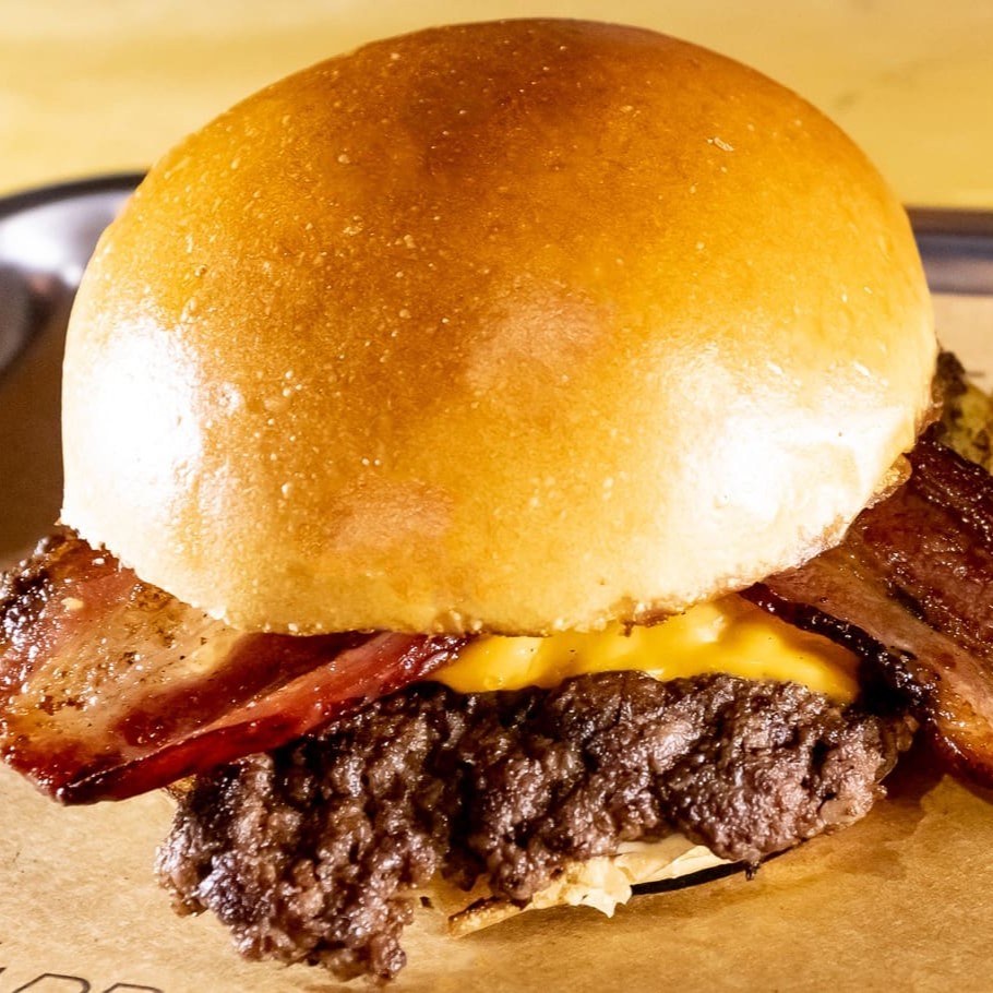 Pão de brioche, Smash Angus 100gr (carne prensada na chapa que gera um sabor maravilhoso), queijo cheddar Polenghi, bacon e maionese silver.
