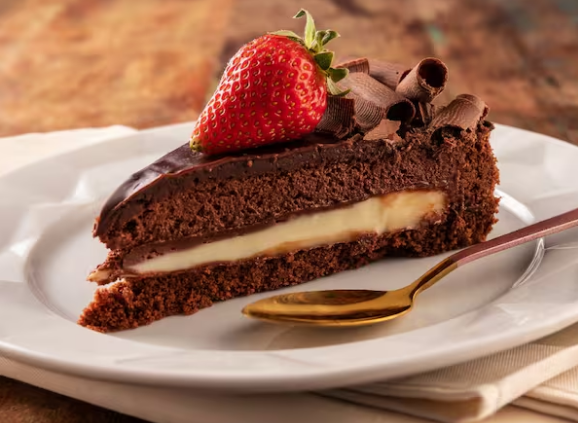 Massa de chocolate recheada com brigadeiro branco, mousse de chocolate aerado, ganache trufado finalizando com raspas de chocolate e morangos