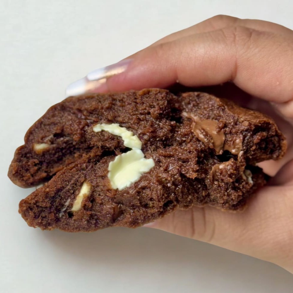 Cookie artesanal recheado feito com massa de cacau com gotas de chocolate nobre ao leite, meio amargo e branco. Você vai amar essa explosão se sabores! Dica: esquente sem o plástico 20 segundinhos no microondas e coma quentinho derretendo na boca! Peso aproximado de 100g.