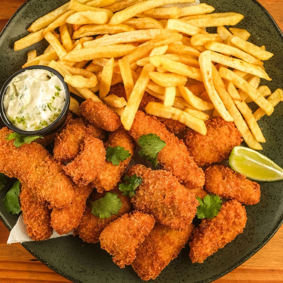 "Releitura do clássico ""fish and chips"". Pedaços de peixe temperado e empanado, servido com batata frita. Acompanha aioli da chef."