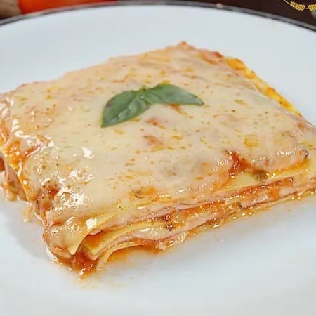 Sedutora Lasanha de Queijo e Presunto ao Pomodoro, da categoria 'Lasanhas Artesanais'. Esta delícia é cuidadosamente preparada com uma massa artesanal de textura perfeita, generosamente recheada com fatias de presunto de qualidade premium. A estrela do prato é nosso molho pomodoro, elaborado a partir de tomates frescos e selecionados, que se une harmoniosamente às camadas de queijo derretido. Fina